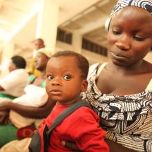 A young mother with her baby on her lap views health videos in the library's maternal health corner.