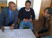 Three men discussing the Open Access indoors