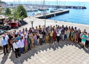 A large group of people, smiling, near the sea in Trieste. 