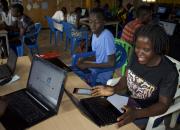 Women and young people learning how to use ICT, with laptops.