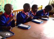 Children at a desk using kindles to read 