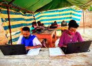 A group of women learning ICT skills at Nyarushanje Community Library. The class is outdoors, and the learners are in a tented enclosure.