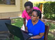 two sitting outside with computers