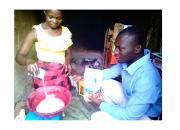 Zariakah Kyozira practising new baking skills at home, watched by Isa Maganda, Isa Maganda, Chief Librarian at Nambi Sseppuuya Community Resource Centre in Uganda.