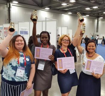 4 award winners joyously showing their trophies and certificates.