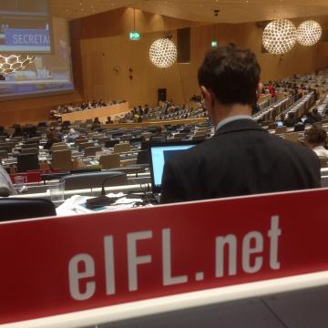 Close-up photo of EIFL's plaque at desk in WIPO's conference hall. The plaque is red with white text.