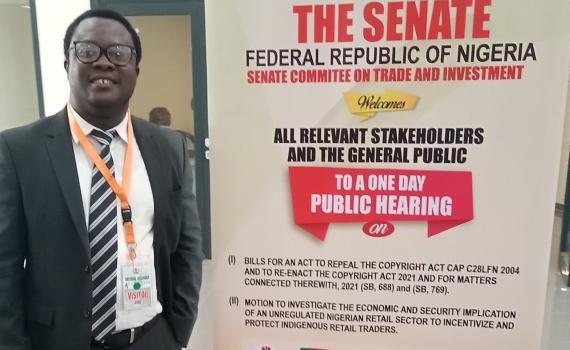 Desmond Oriakhogba, Senior Lecturer, University of the Western Cape, South Africa, with a poster advertising the 2021 Senate hearing on the Copyright Bill in Lagos, Nigeria.