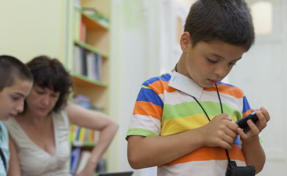 Child in the library using a mobile phone