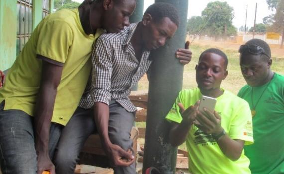 A group of young people looking at the screen of a smartphone.