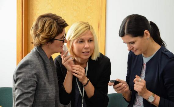 Three workshop participants listening to audio devices for print disabled people.