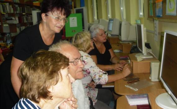 A group of senior people learning internet skills in the library. 