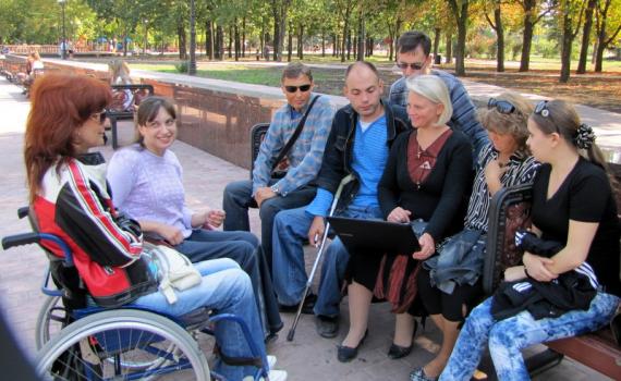 The library's training takes place in the park, or in any other venue where learners feel secure and comfortable. Group of trainees, some in wheelchairs, in the park.