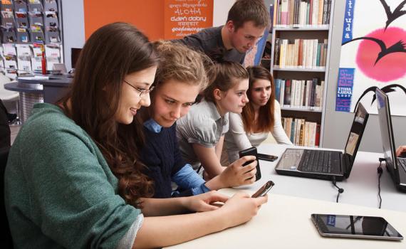 Teenagers using tablet and desktop computers in the library. Photo by Adam Mikosz.