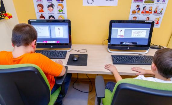 Two children working on computers, learning financial literacy skills, in the library.