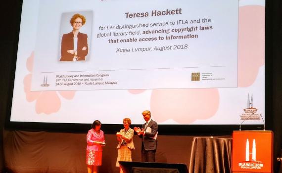 Teresa Hacket receives the award at the IFLA congress. Backdrop is of a banner of Teresa. Teresa Hacket receives the award at the IFLA congress. Backdrop is of a banner of Teresa.